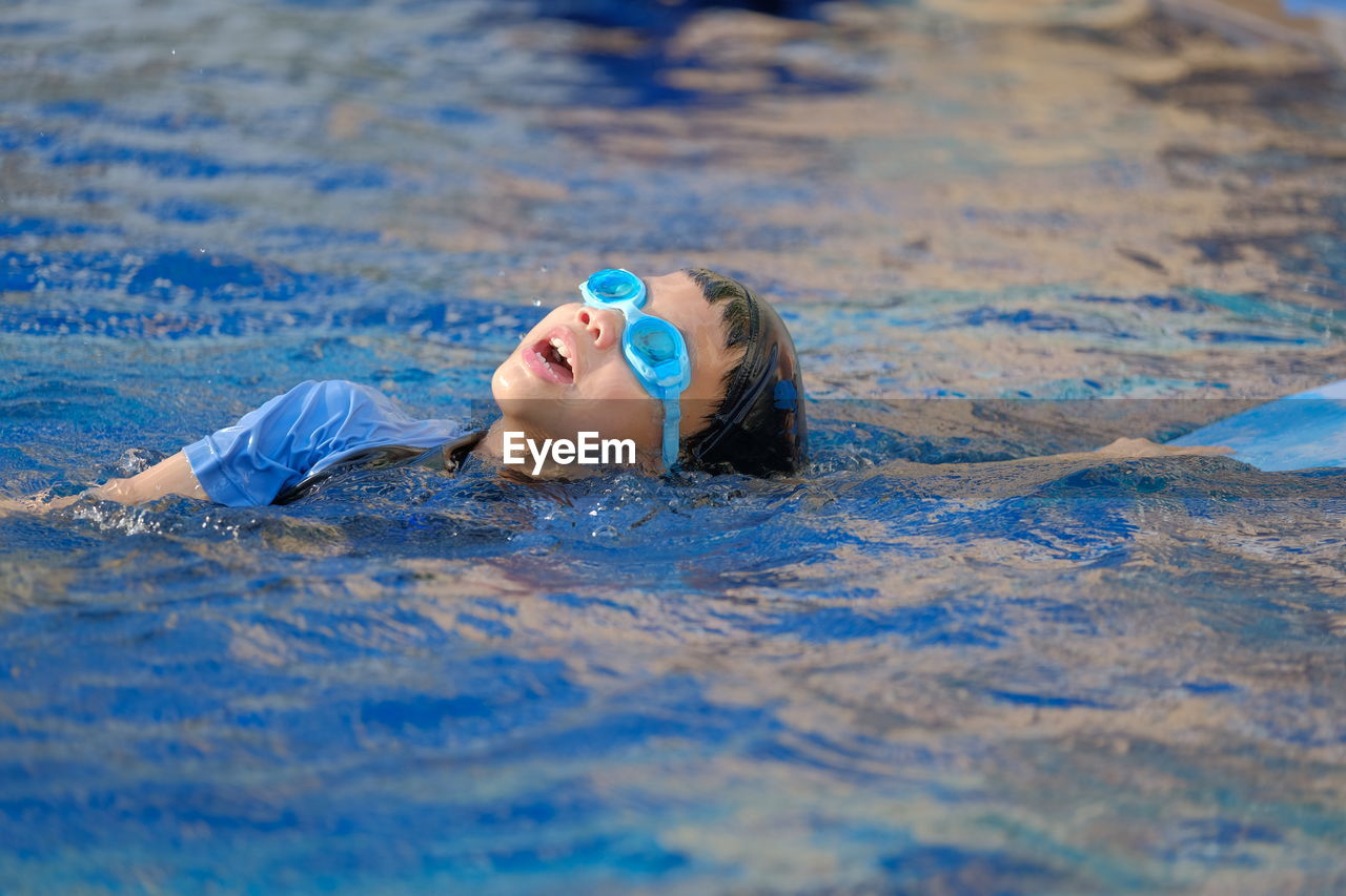 PORTRAIT OF BOY SWIMMING IN POOL