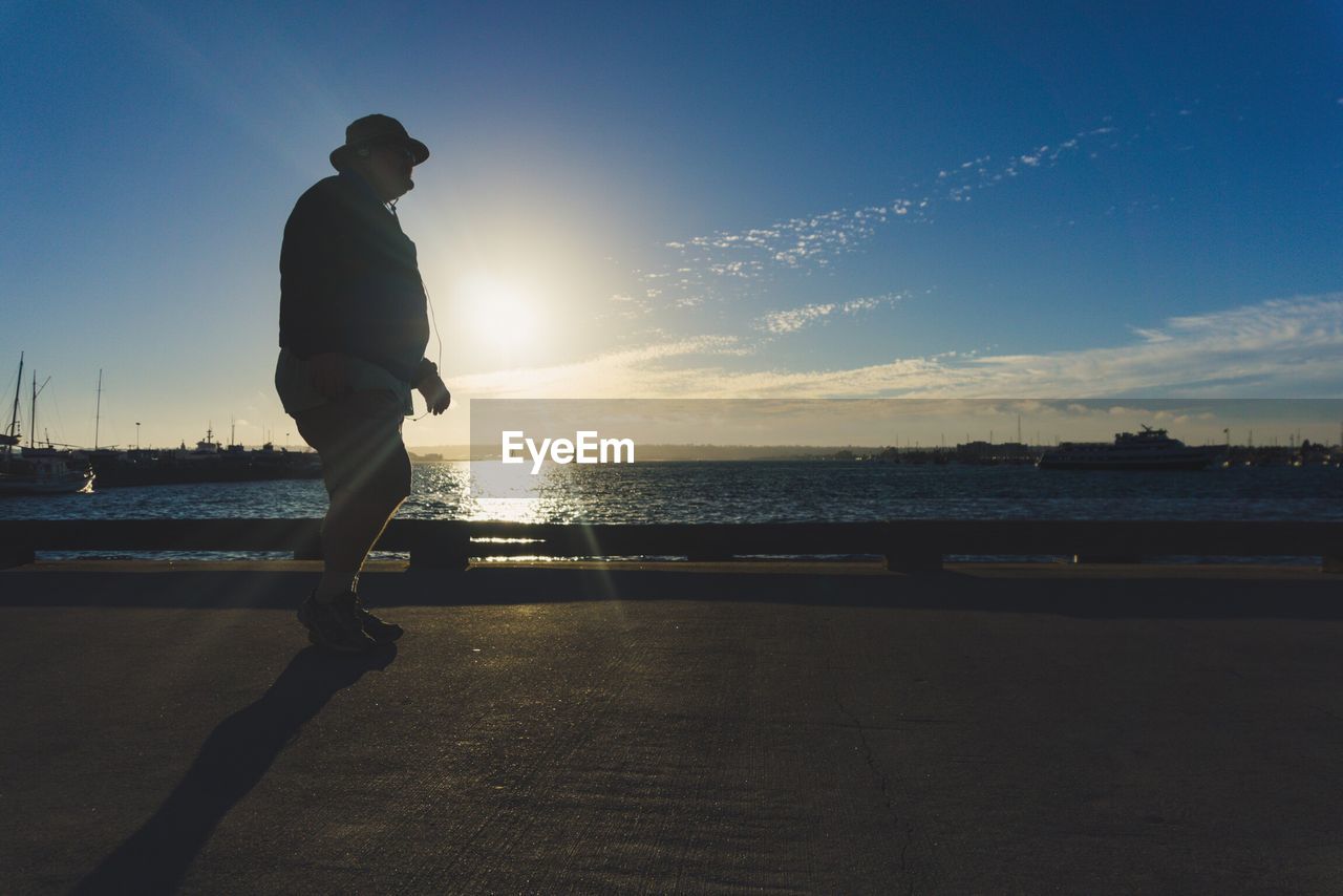 Man standing on beach against sky during sunset