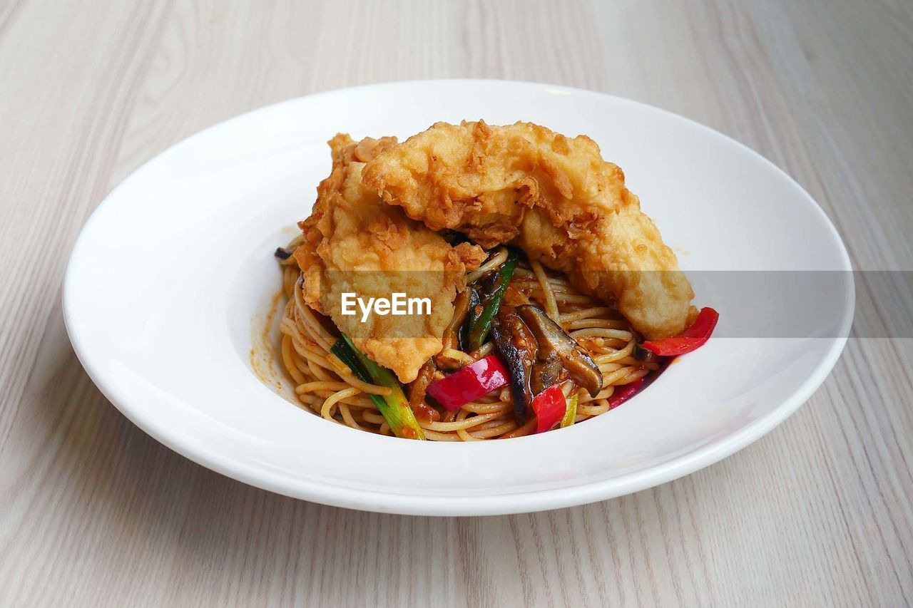 High angle view of fried chicken with pasta in plate on table