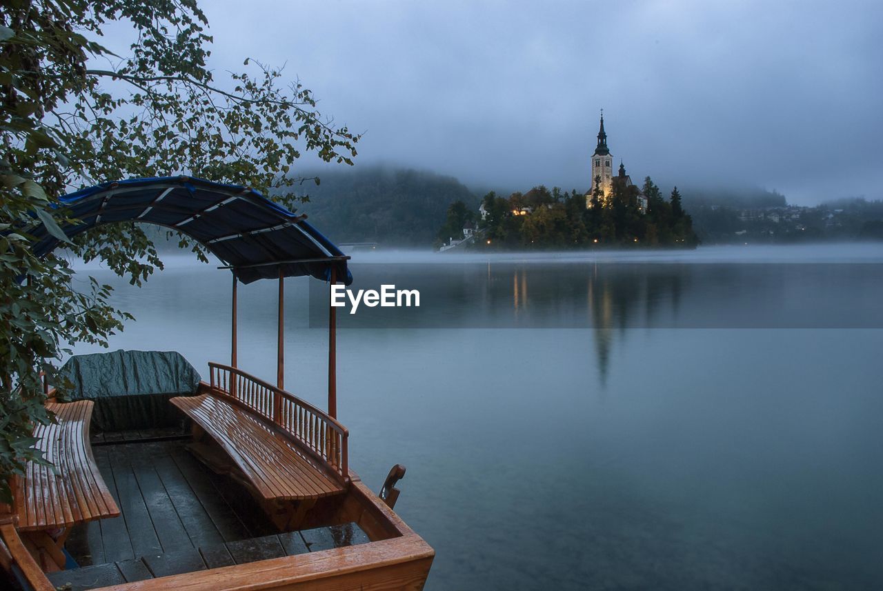 View of building by lake against sky