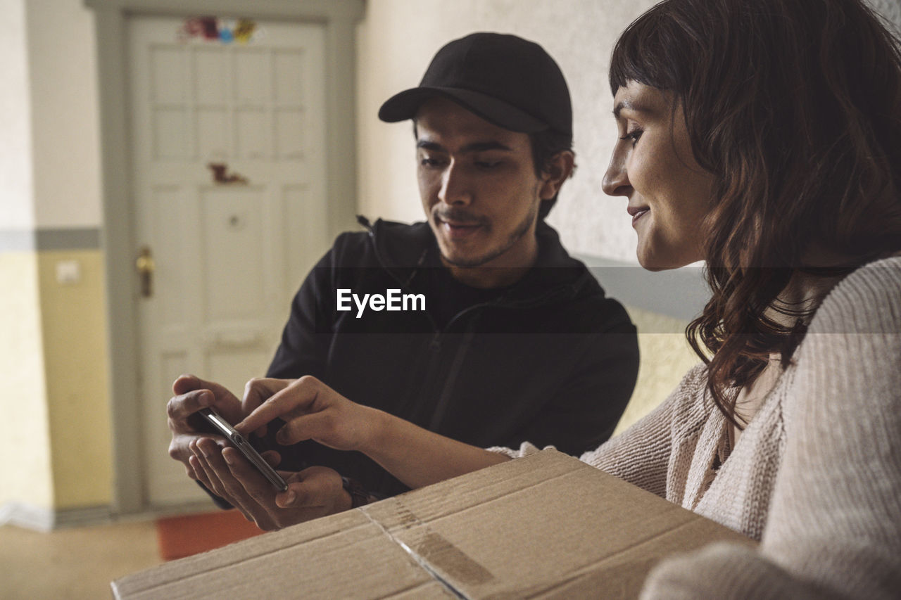 Smiling customer signing on smart phone during package delivery