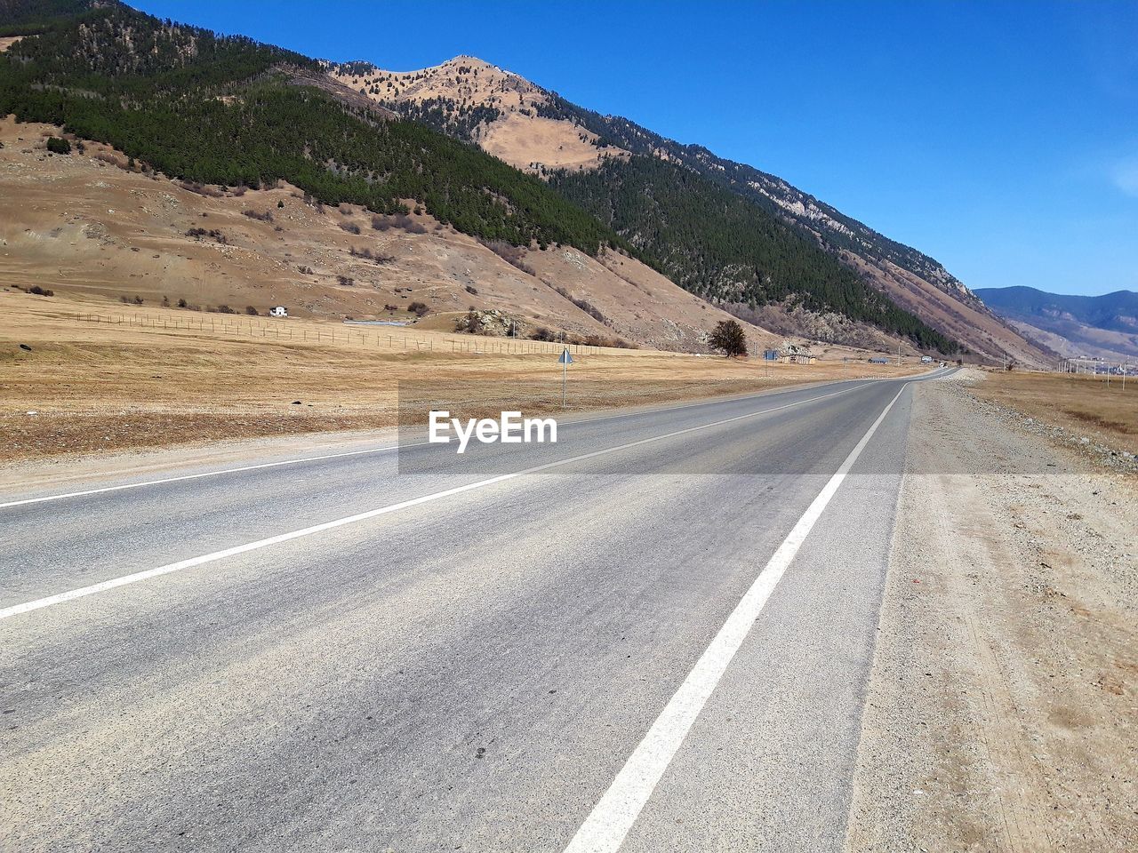 Road by mountains against sky