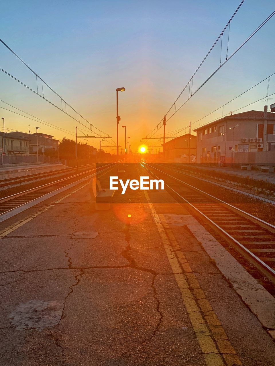 Railroad station platform against sky during sunset