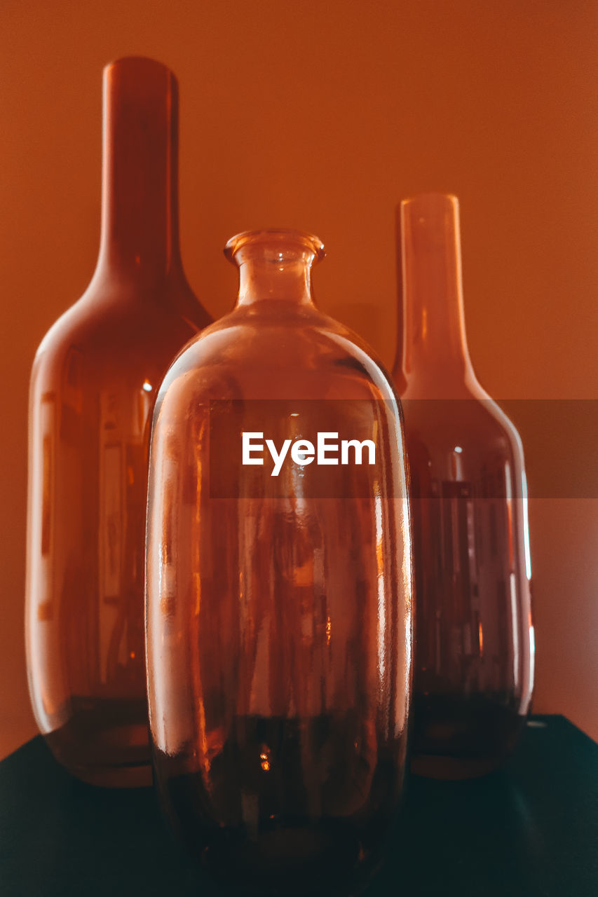Three orange colored glass bottles against orange colored background
