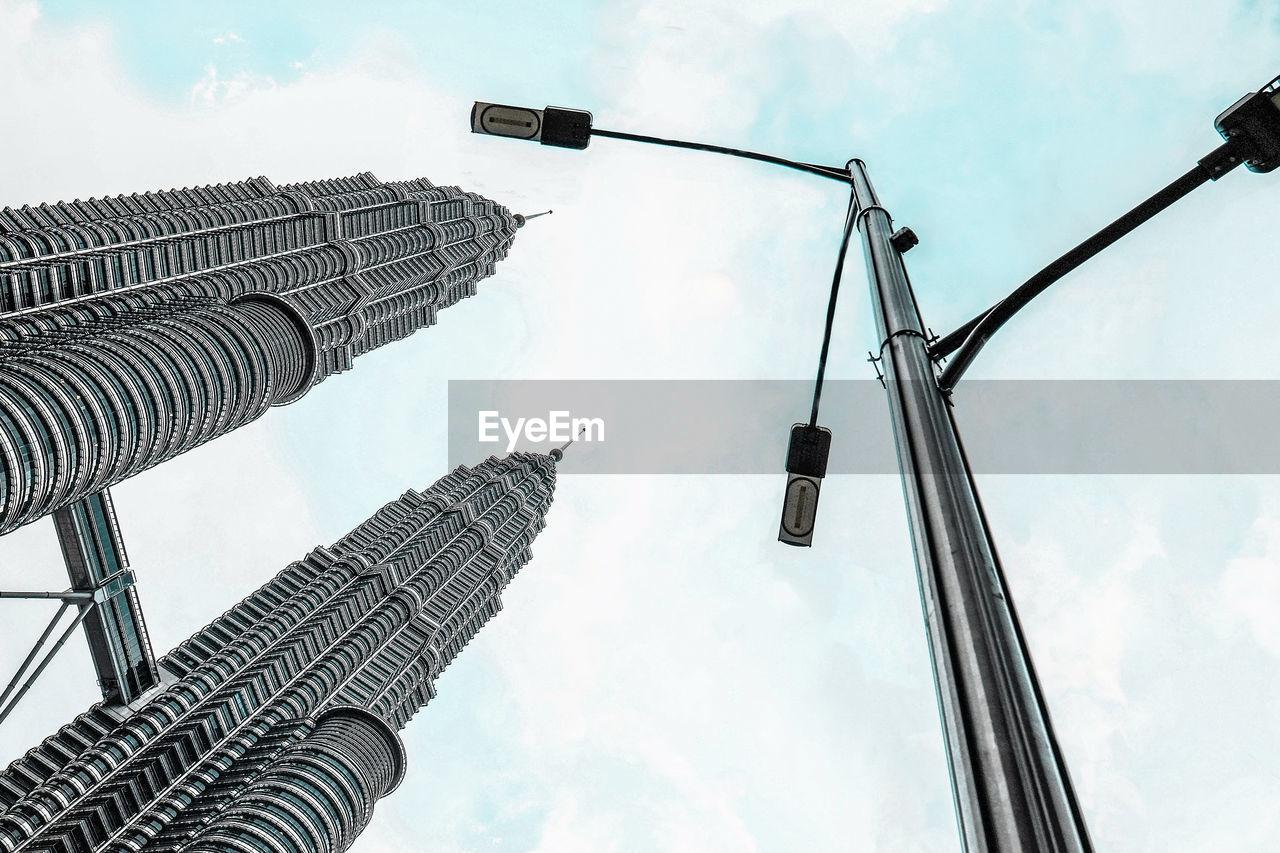 Low angle view of street light and petronas towers against sky