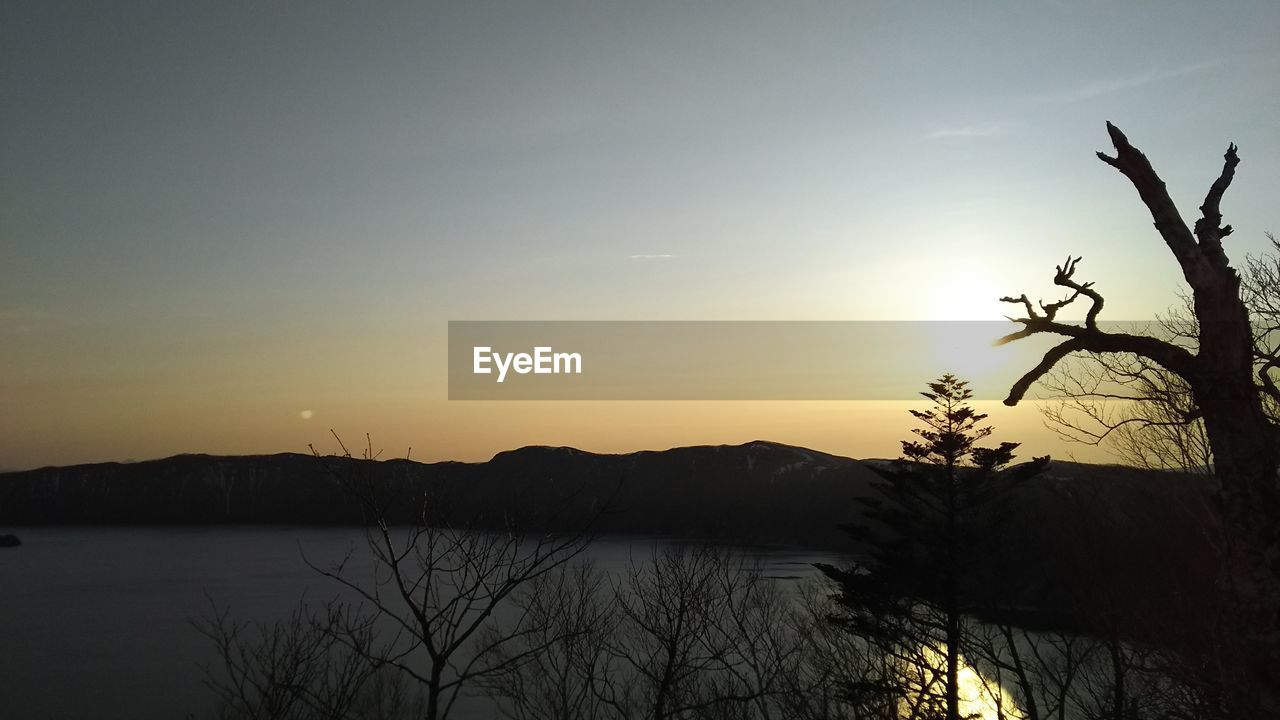 SCENIC VIEW OF LAKE BY SILHOUETTE MOUNTAIN AGAINST SKY