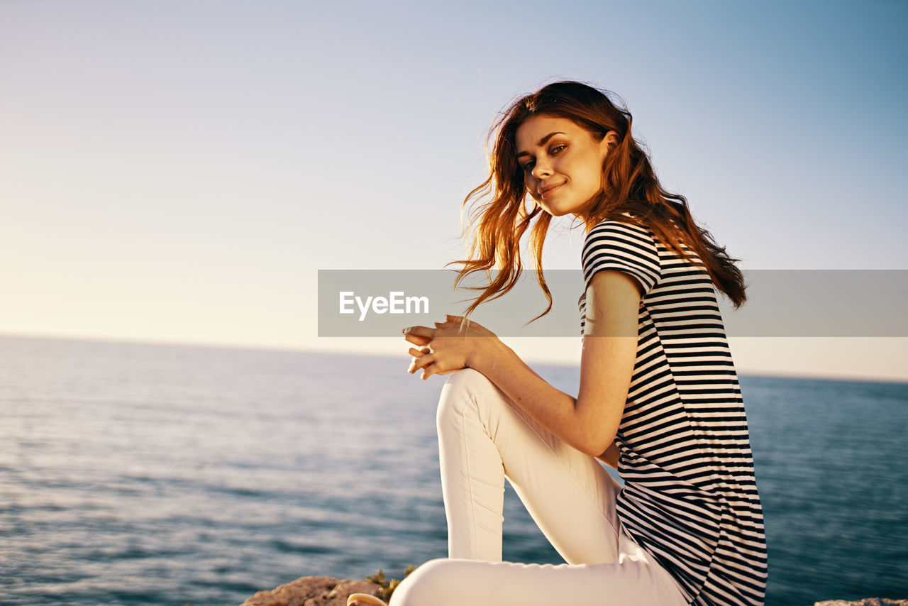 Beautiful woman smiling at sea against sky