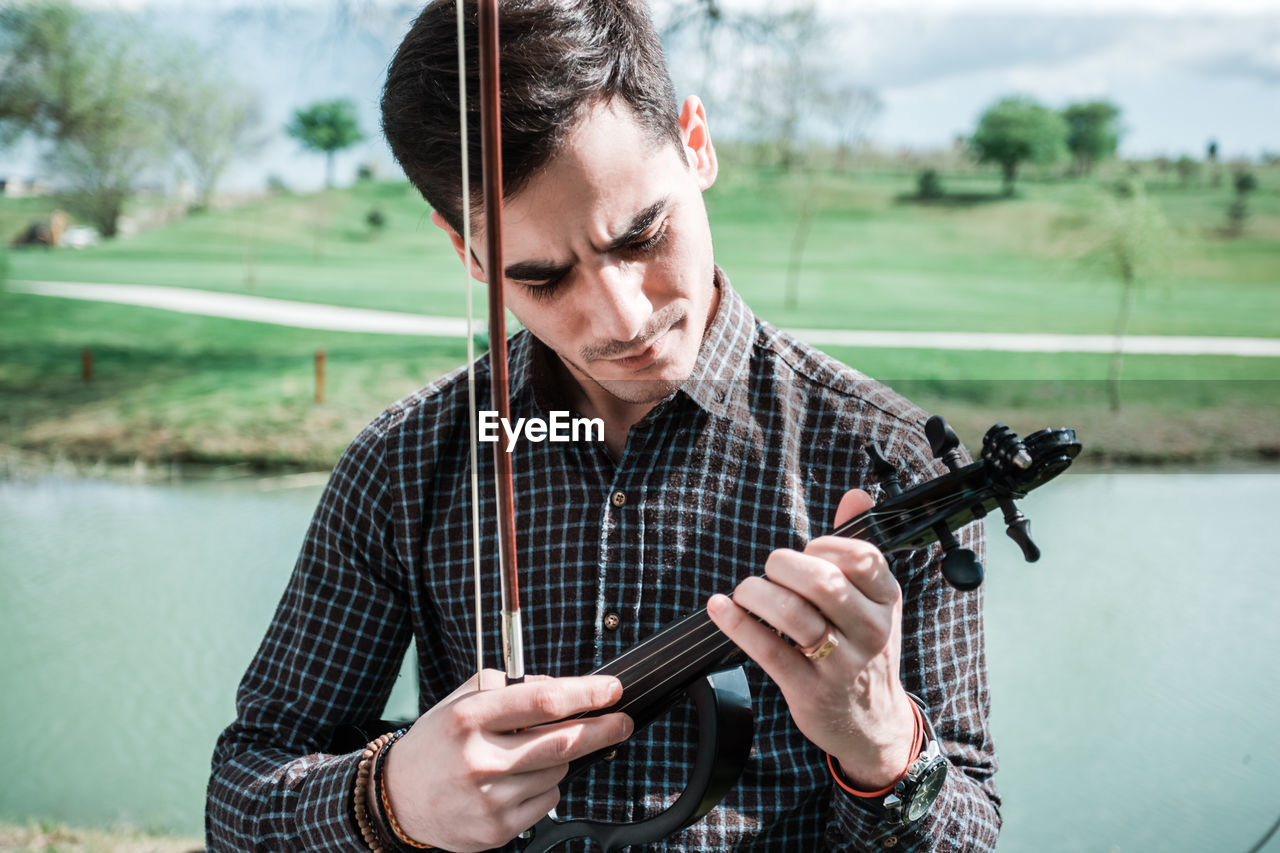 PORTRAIT OF MAN LOOKING AT CAMERA WHILE HOLDING LAKE