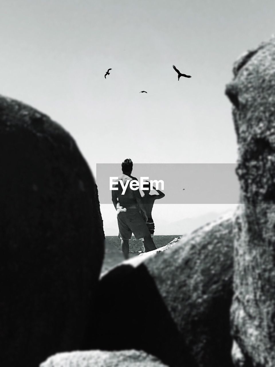 Rear view of father and son at beach against sky