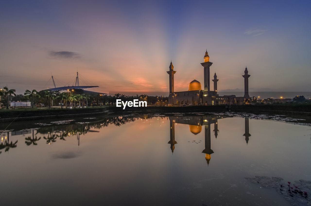 Reflection of tengku ampuan jemaah mosque in lake against sky during sunrise