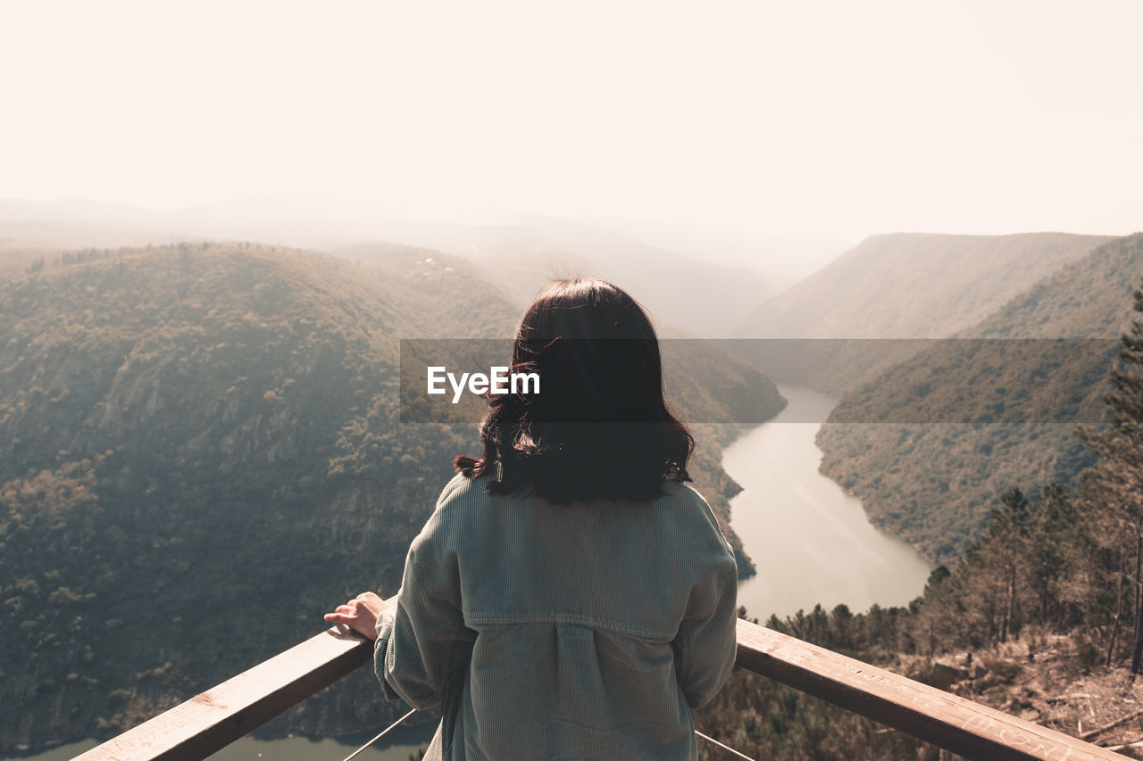 REAR VIEW OF WOMAN LOOKING AT MOUNTAIN RANGE