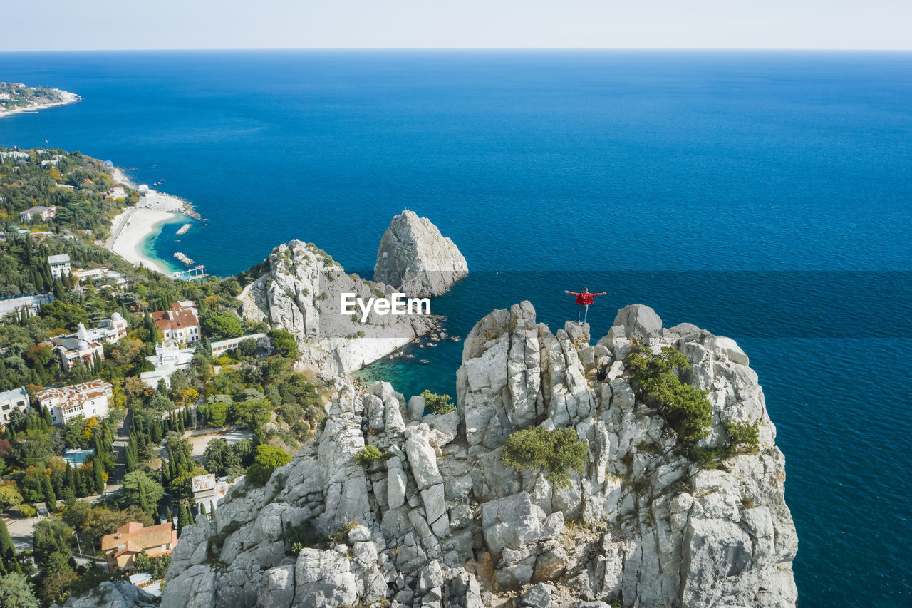 Man tourist in red jacket standing on the rock top of cat mountain enjoying  simeiz area. crimea