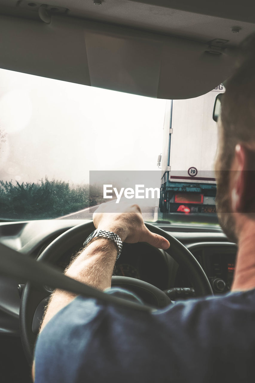 REAR VIEW OF MAN TRAVELING IN CAR