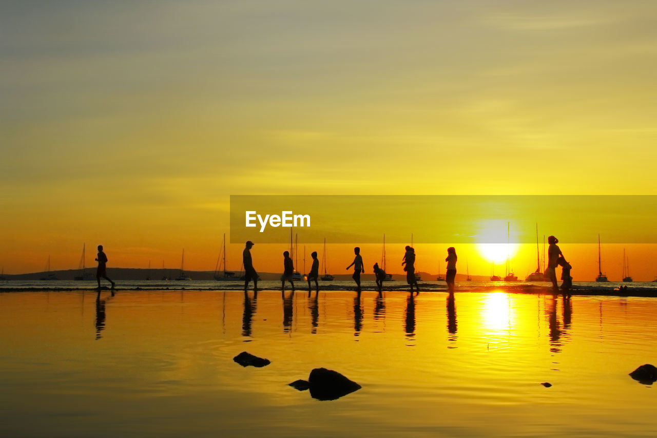 Silhouette people in sea against yellow sky during sunset in east nusa tenggara indonesia