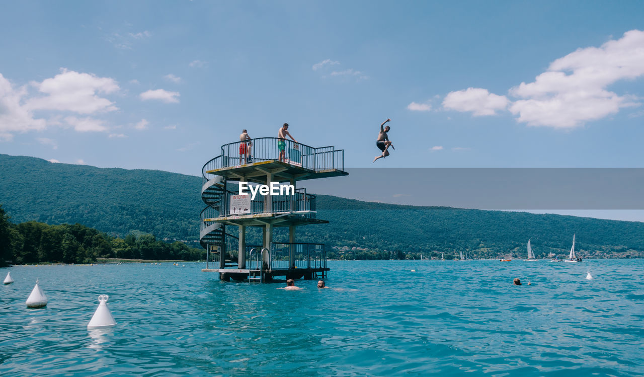 People jump into lake annecy from a diving board