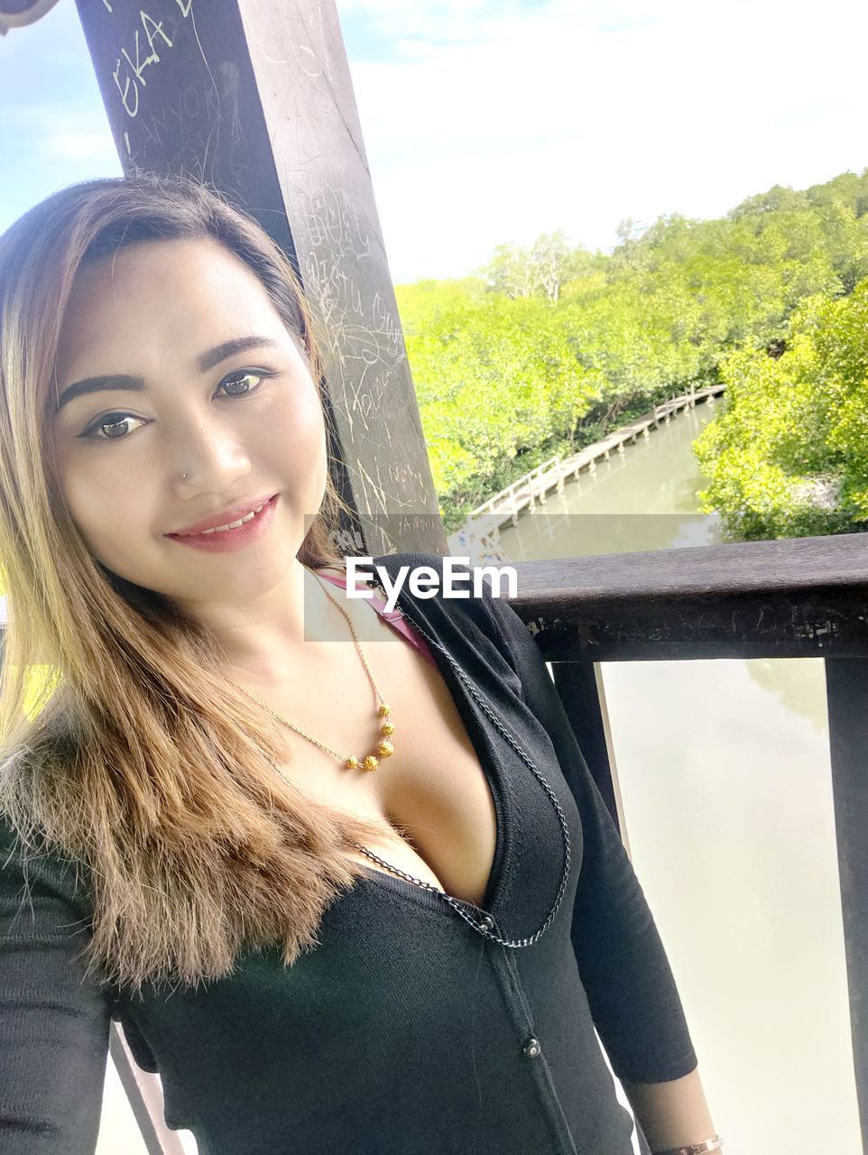 PORTRAIT OF SMILING YOUNG WOMAN SEEN THROUGH WINDSHIELD