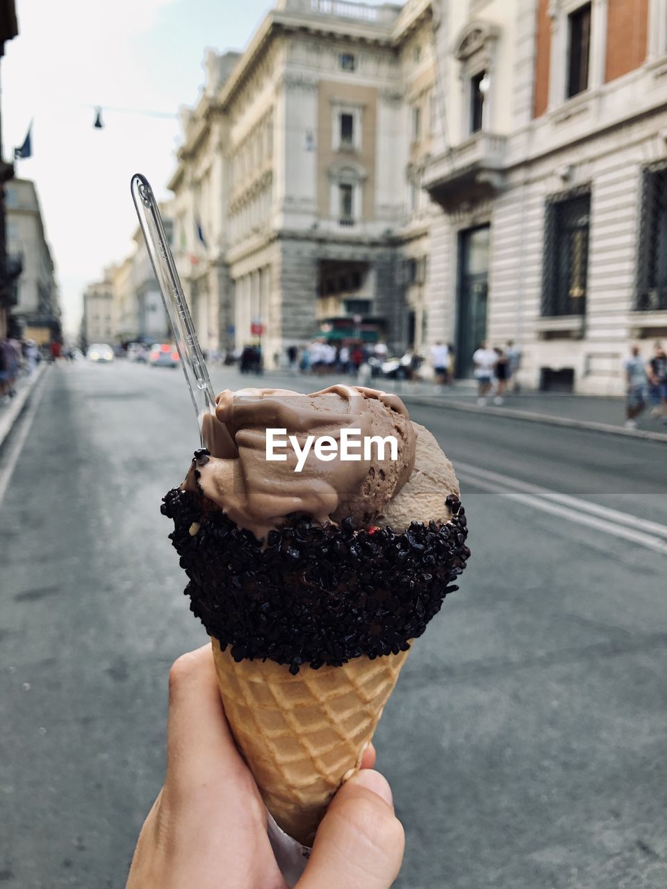 Cropped hand of woman holding ice cream cone on street