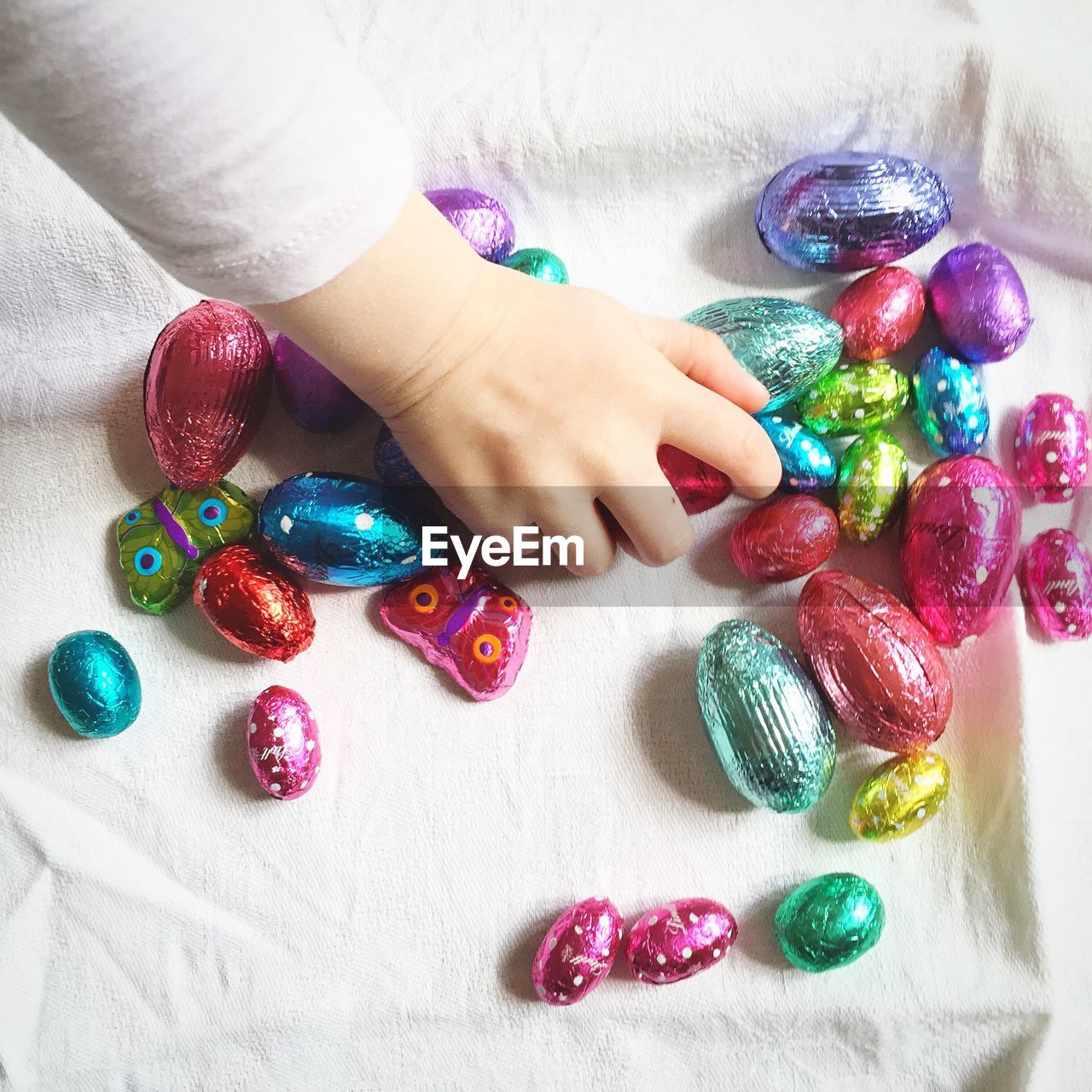 Small girl playing with multi colored egg-shaped candies