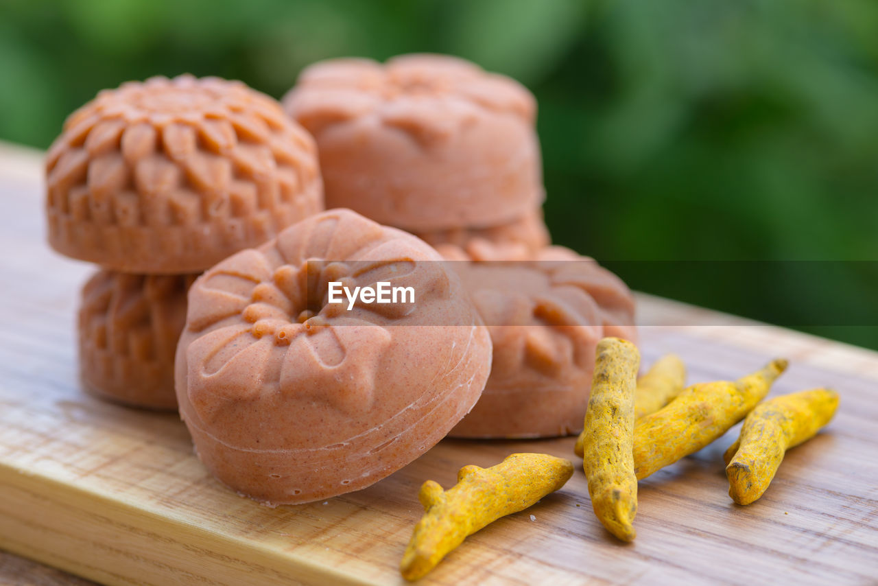 Round orange soap in the form of flowers with turmeric on a green background