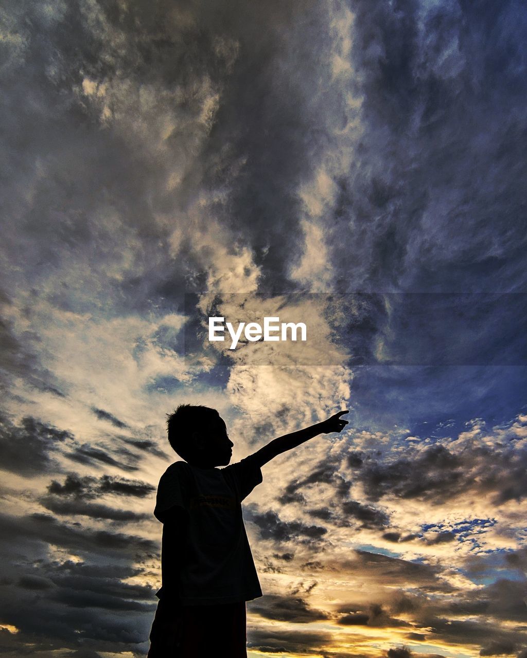 REAR VIEW OF BOY STANDING AGAINST SKY