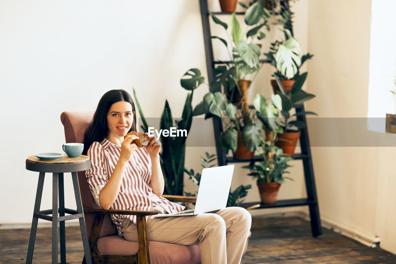 Young woman using phone while sitting on table