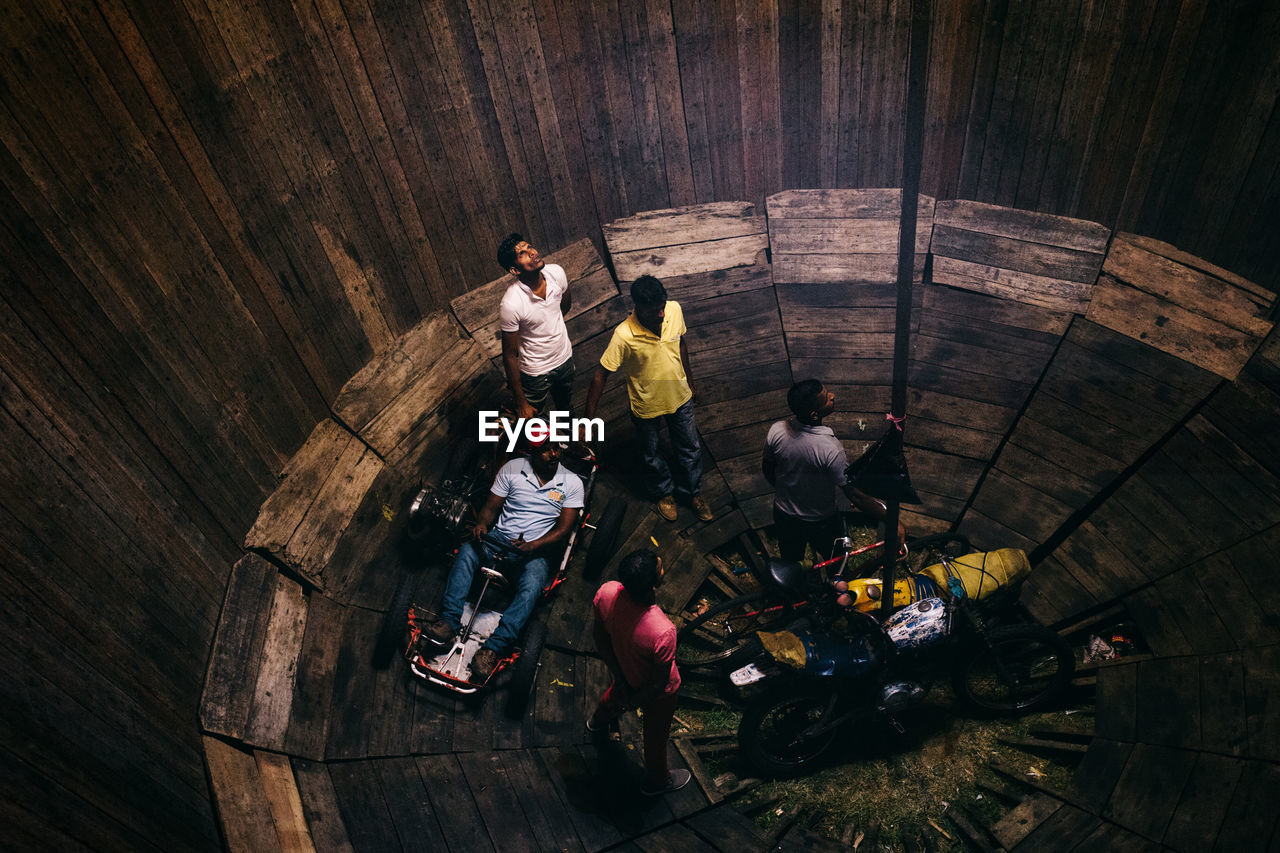 HIGH ANGLE VIEW OF PEOPLE STANDING ON WOOD