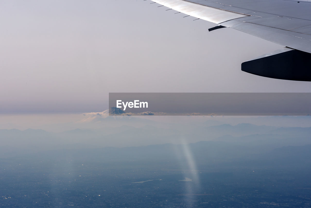 Airplane flying over fuji mountain against sky