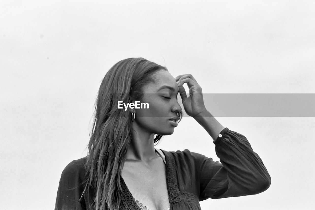 Portrait of young woman looking away against white background