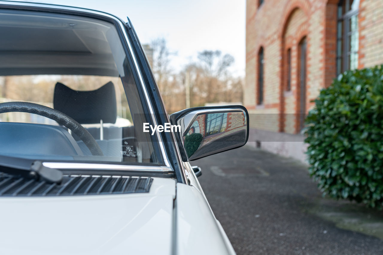 Side mirror with reflections and a brick building in the background