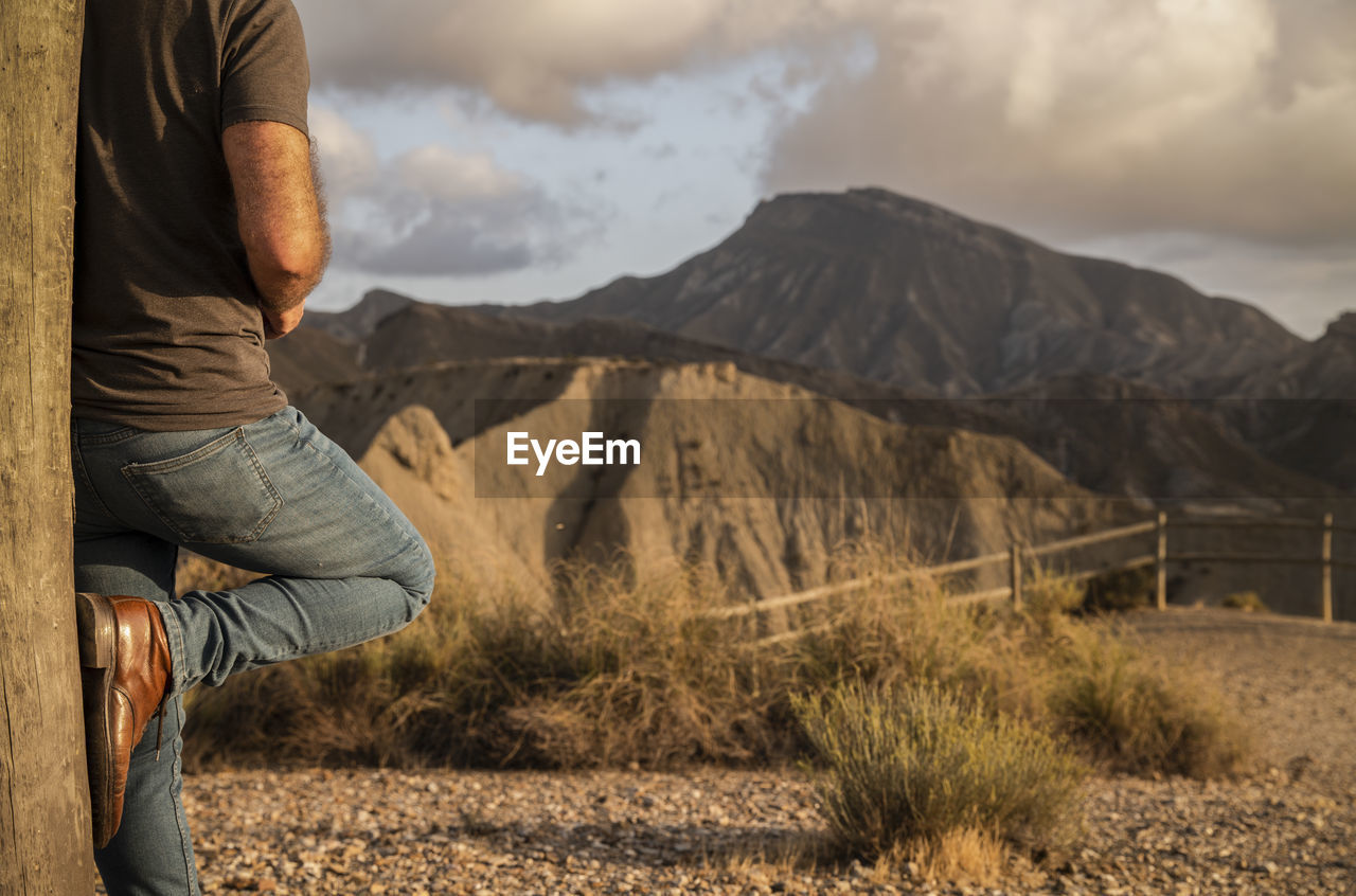 Low section of man relaxing on land against sky, in tabernas desert, almeria, spain