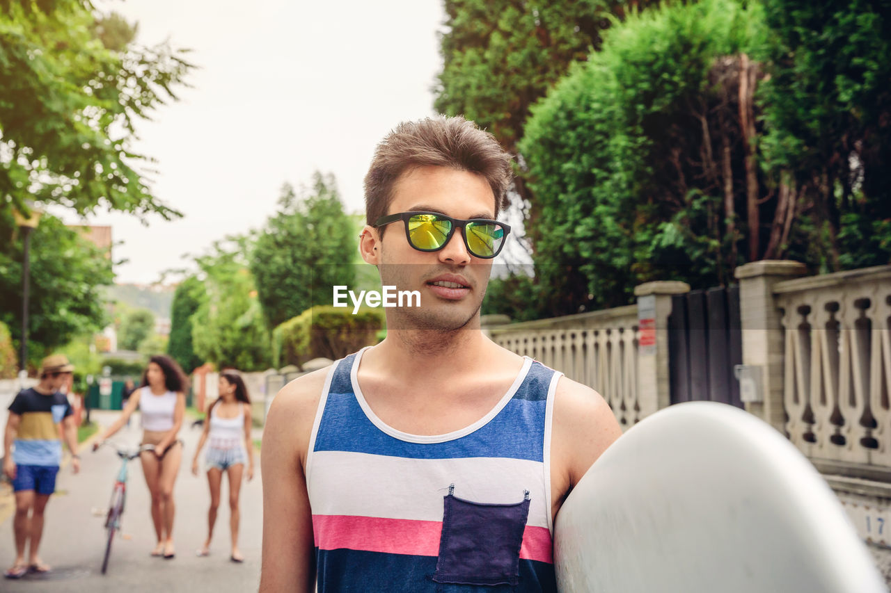 Young man wearing sunglasses with friends in background on road