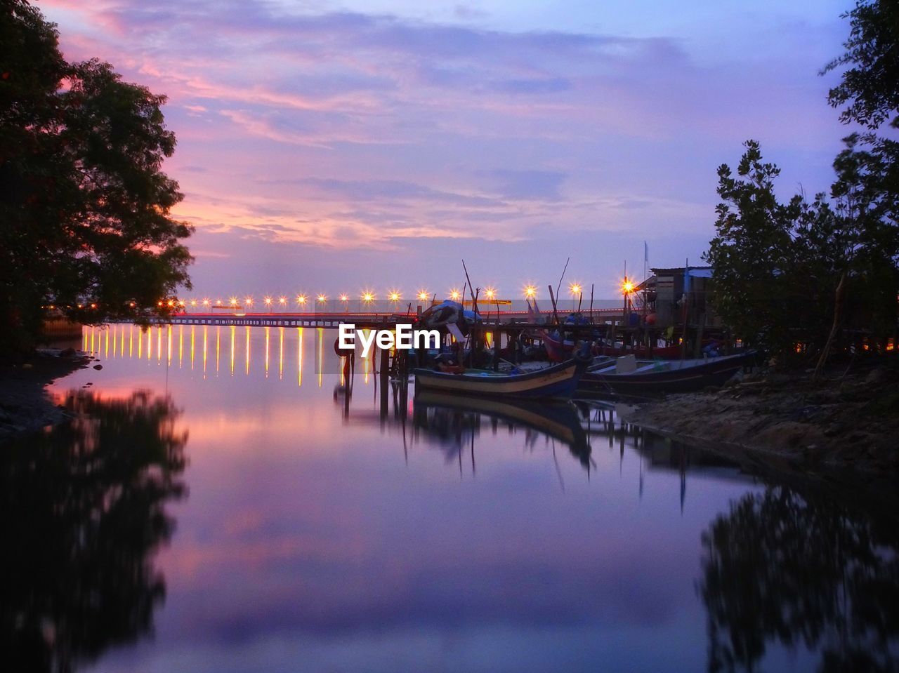 Sailboats moored in lake against sky at sunset