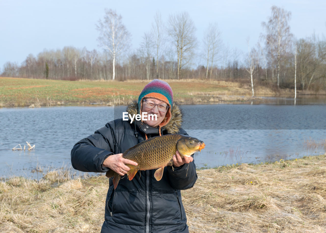 A happy fisherman on the lake shore, caught carp in a woman's hand, amateur carp fishing