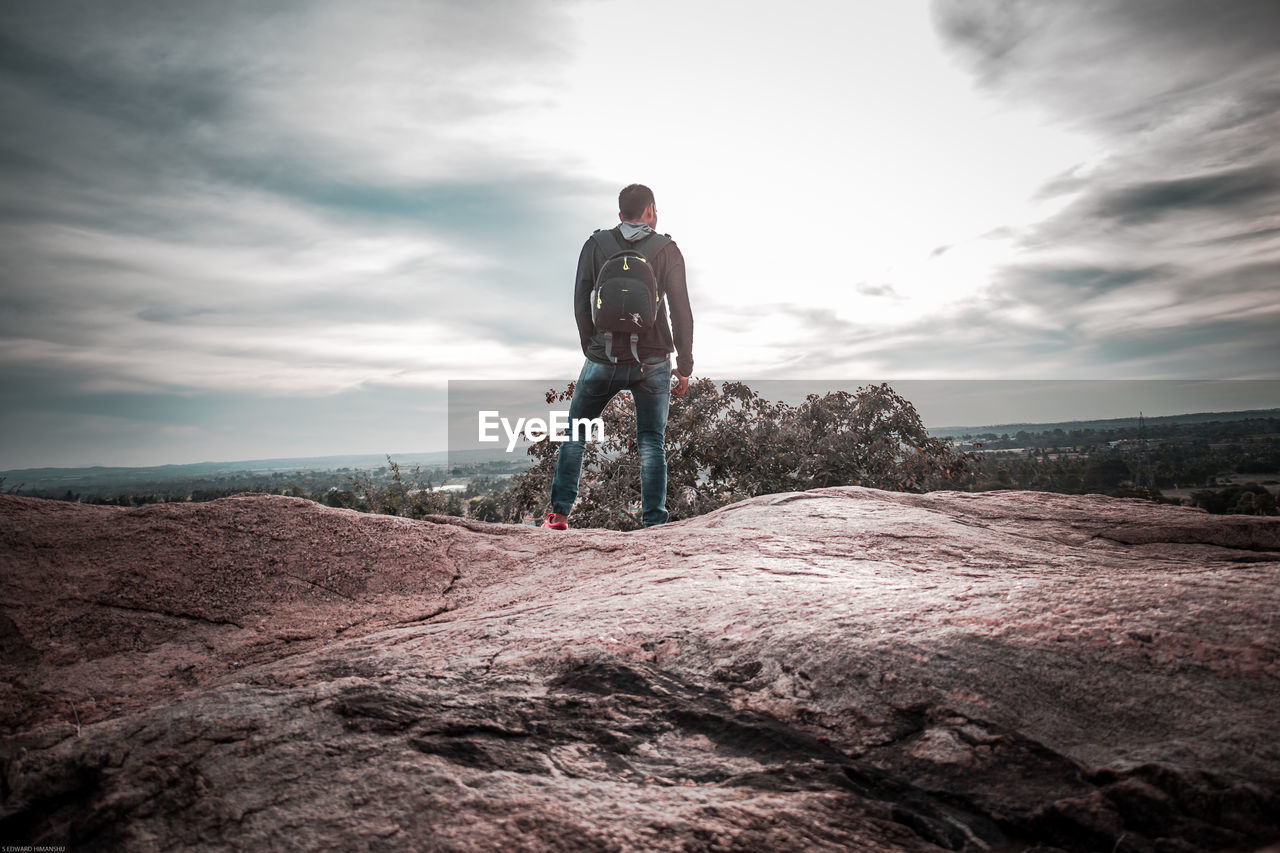 MAN RIDING BICYCLE ON LANDSCAPE AGAINST SKY