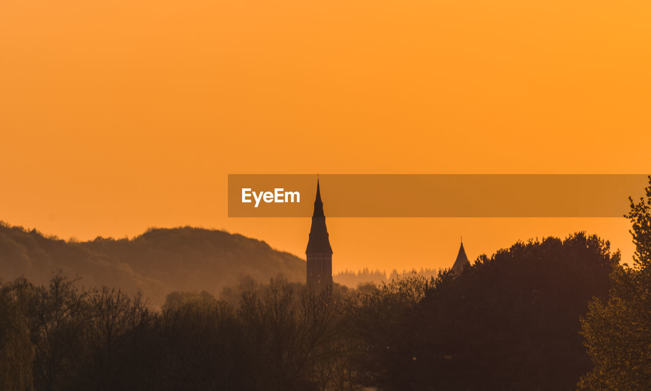 SILHOUETTE OF TEMPLE BUILDING AGAINST ORANGE SKY