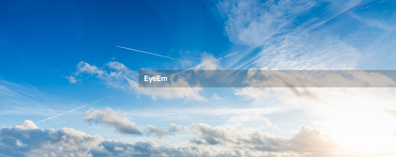 LOW ANGLE VIEW OF VAPOR TRAILS IN BLUE SKY