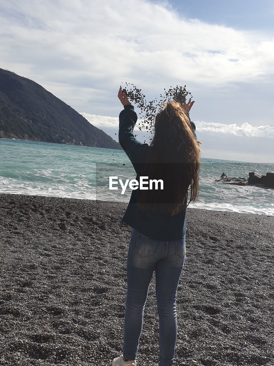 REAR VIEW OF WOMAN STANDING AT BEACH