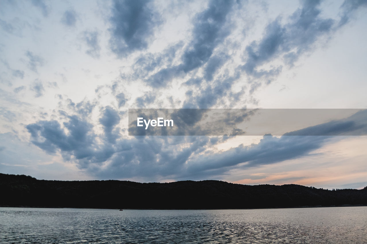 SCENIC VIEW OF LAKE BY SILHOUETTE MOUNTAINS AGAINST SKY