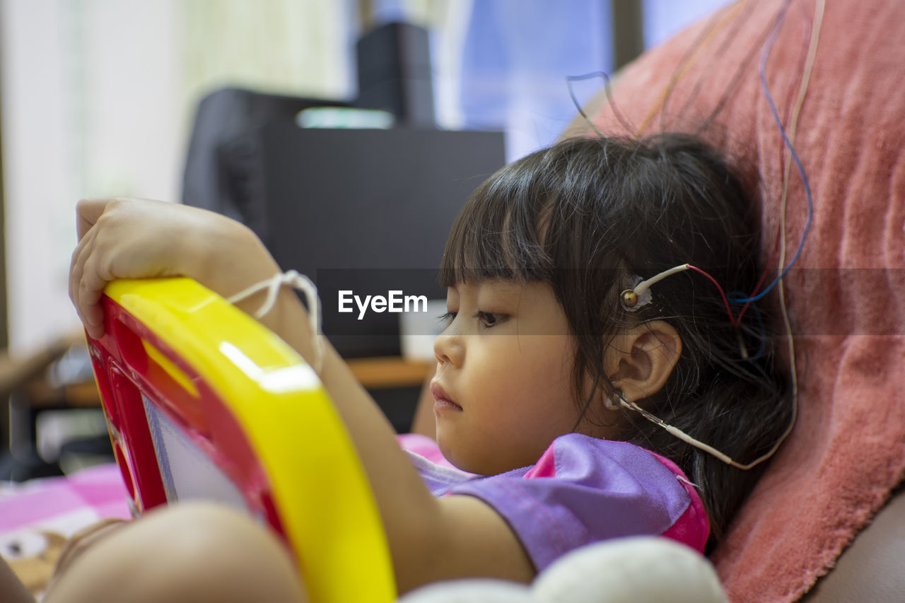 Cute girl with electrodes on head relaxing on chair