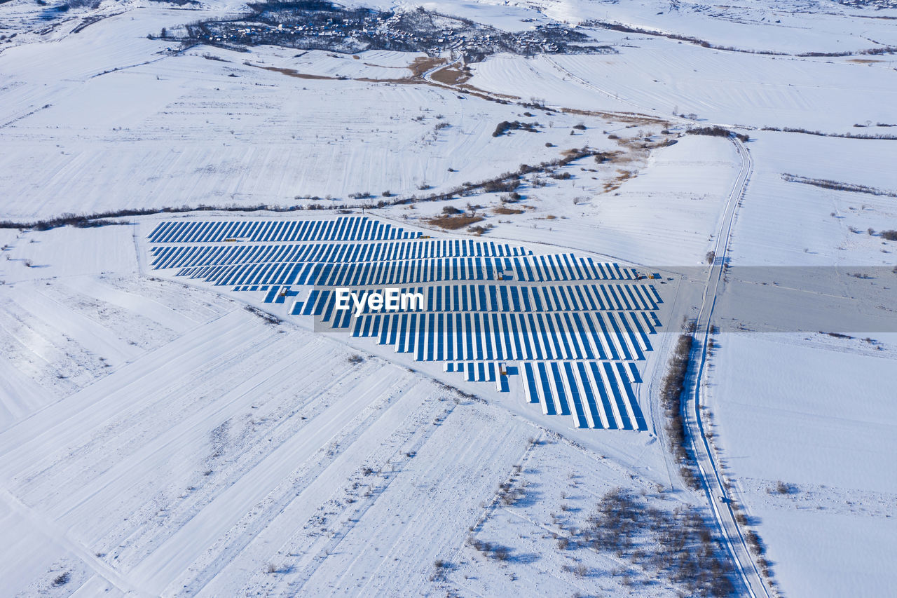 Aerial drone view of snow covered solar panel park, photovoltaic power station in the winter