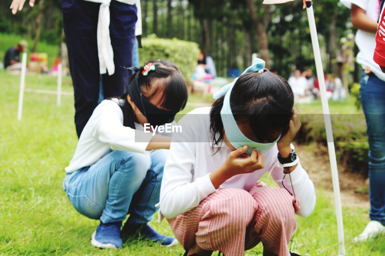 REAR VIEW OF GIRL SITTING ON FIELD