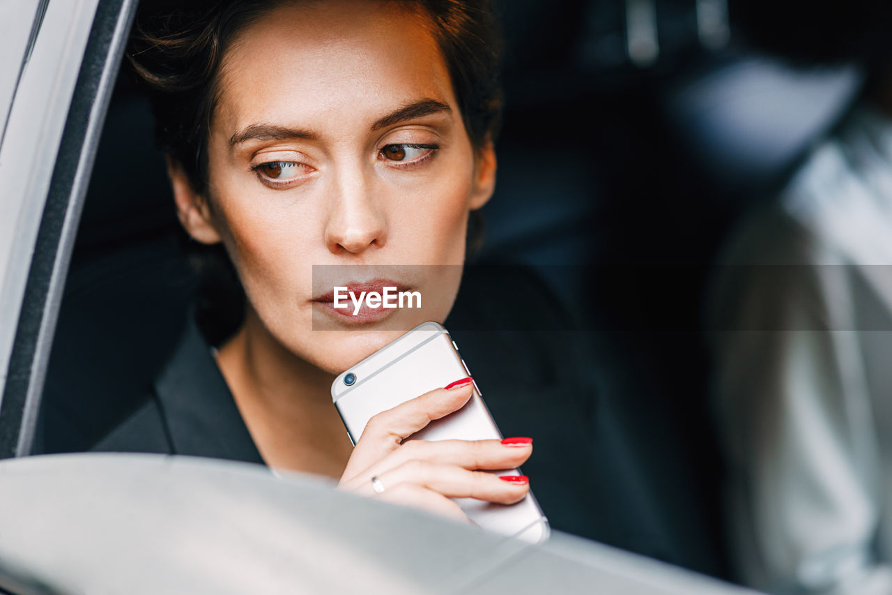 Close-up of woman holding smart phone sitting in car