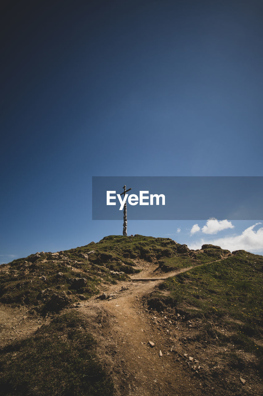 Low angle view of religious cross on mountain against blue sky