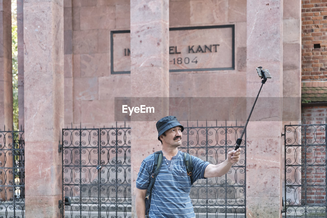 Senior asian tourist with backpack taking selfie in front of grave of philosopher immanuel kant 