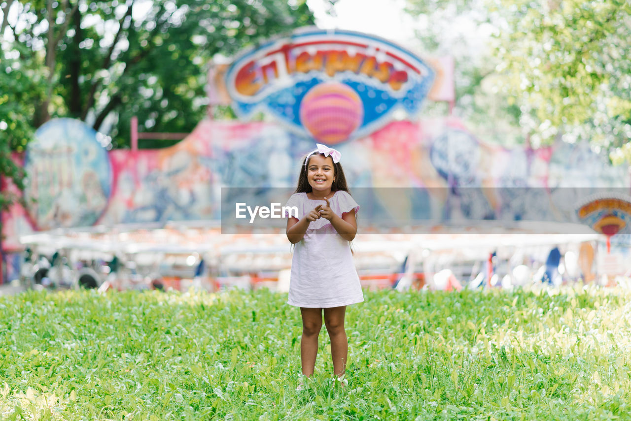 A cute little girl in the park is holding popcorn in her hands and smiling with a big smile