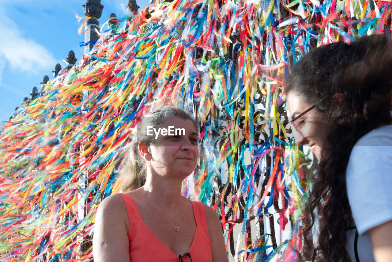 Portrait of two women placing colored ribbons on the church grid. 