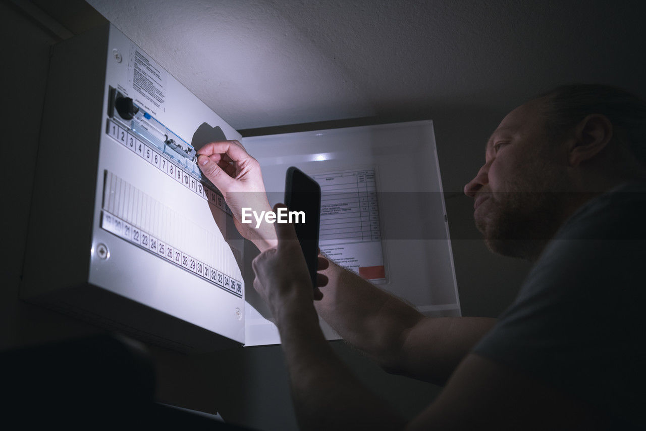 Electrician checking electrical cabinet at night