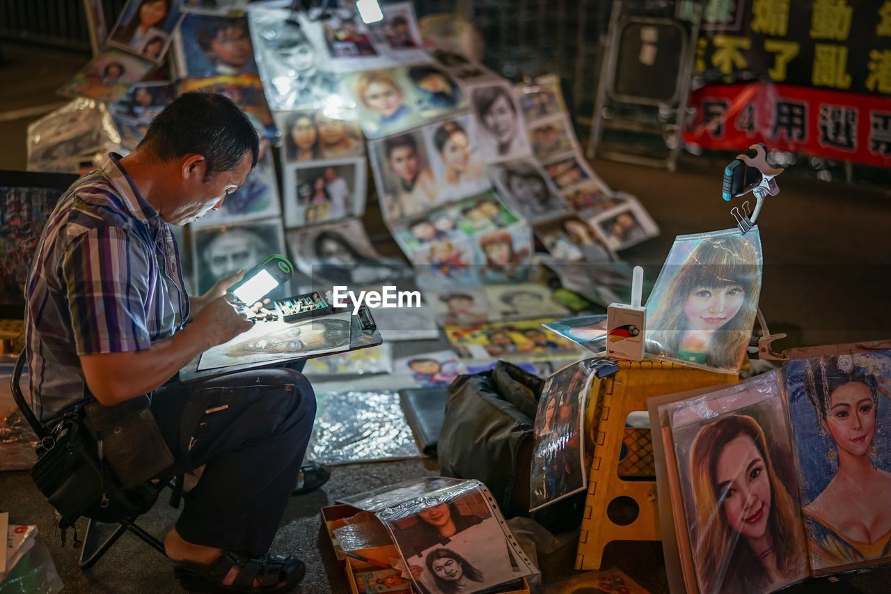 Portrait painter selling his paintings in flea market