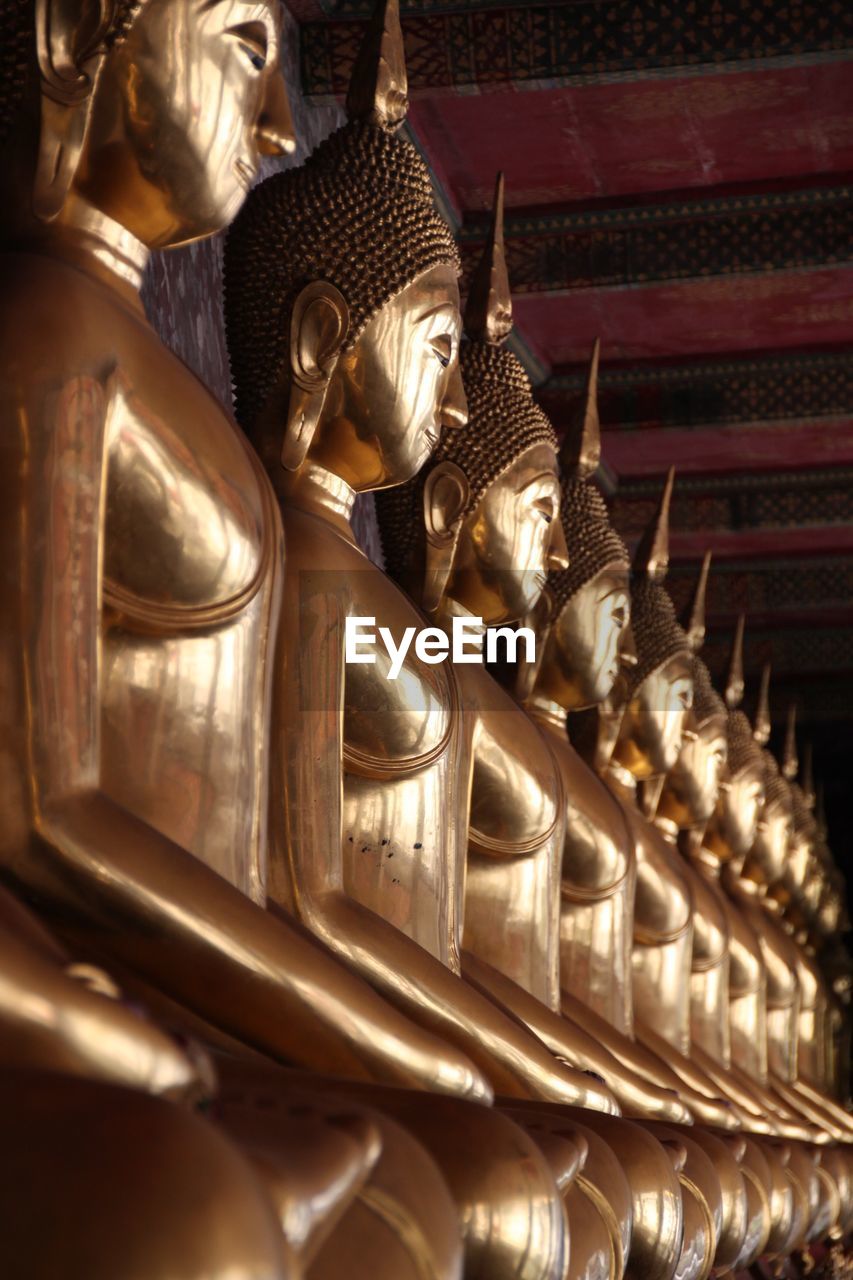 Rows of golden buddha statues at temple wat suthat