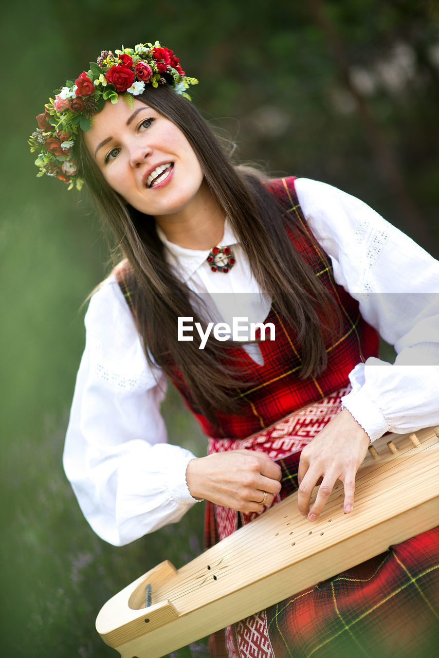 Beautiful musician wearing flowers wreath while playing string instrument